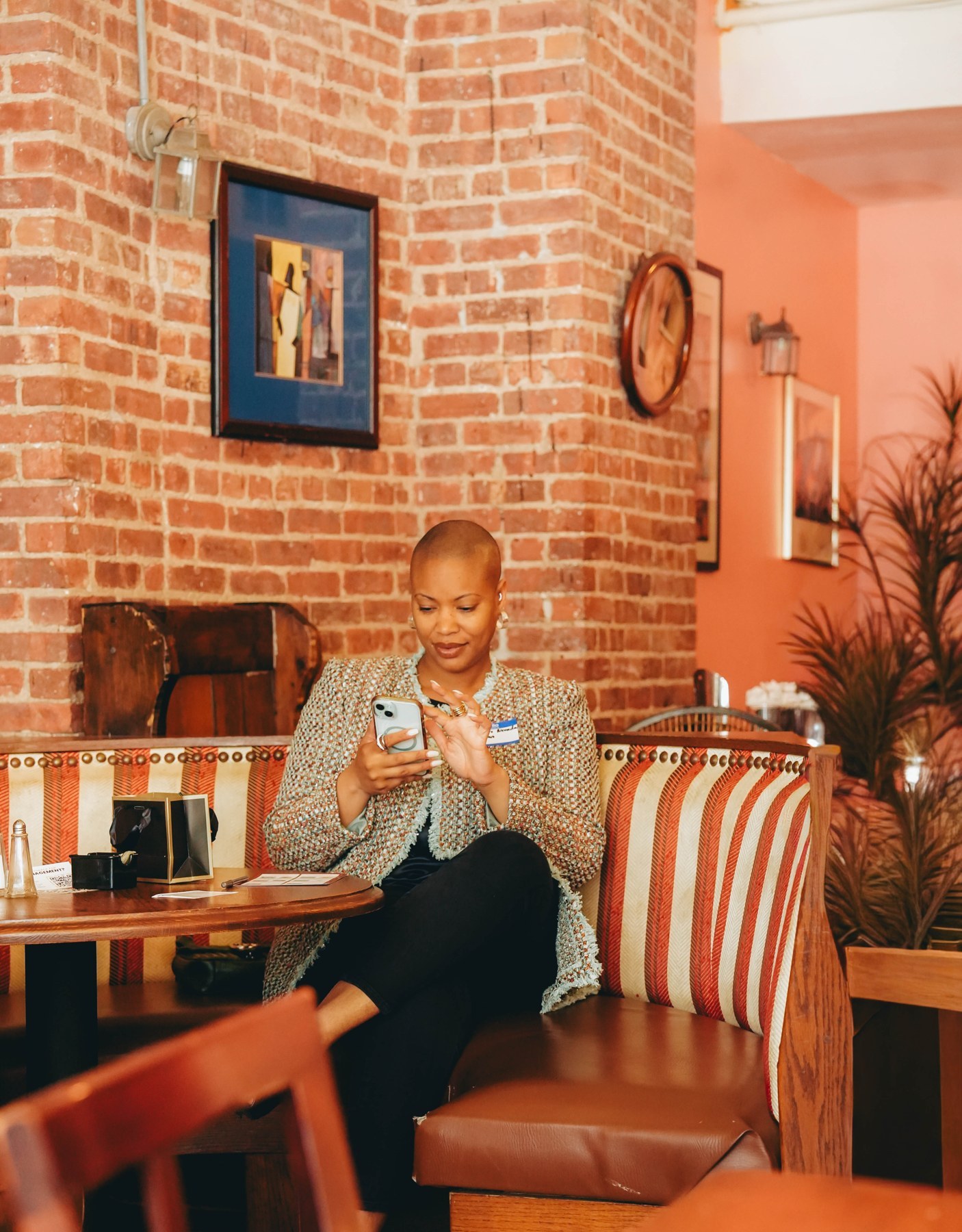 Brennan Nevada Johnson seated against a brick wall, checking her phone